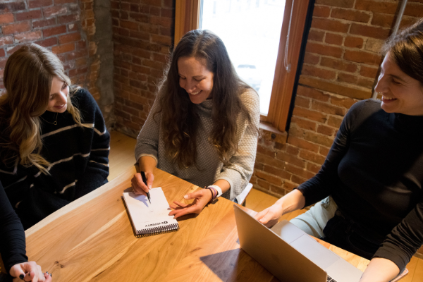 Group of women working around a desk with a laptop